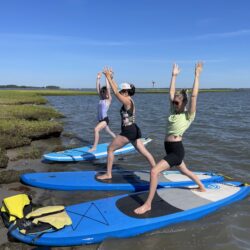 people doing yoga on a paddle board